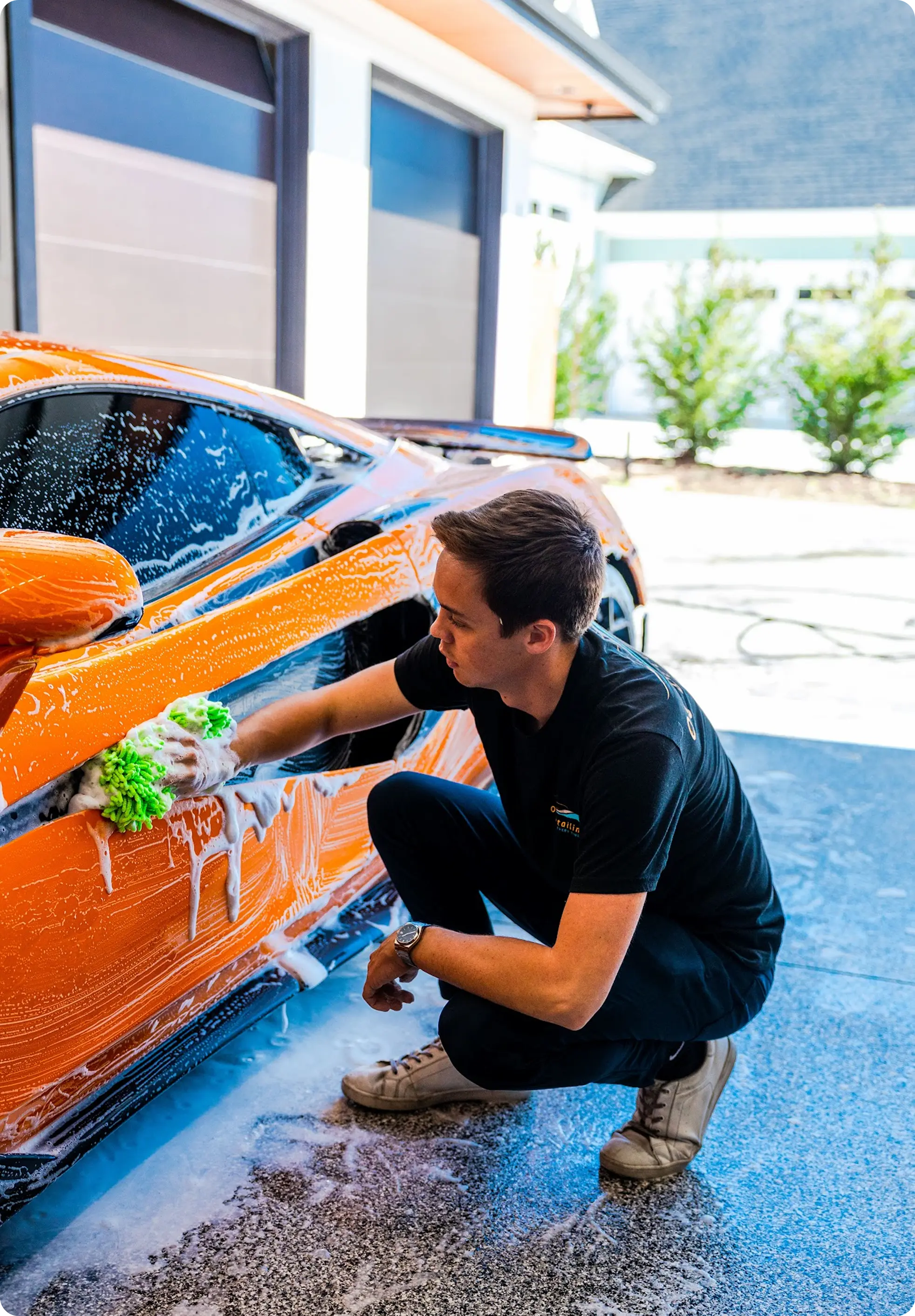 Person washing the exterior of an orange McLaren